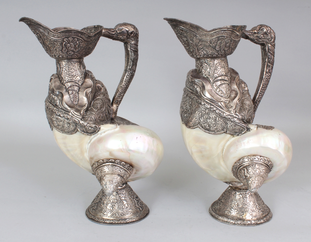 AN UNUSUAL PAIR OF TIBETAN SILVER-METAL MOUNTED NAUTILUS SHELLS, each shell with elaborately