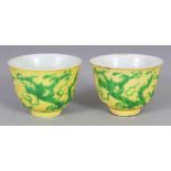 A PAIR OF MING STYLE GREEN & YELLOW ENAMELLED PORCELAIN DRAGON WINE CUPS, each base with a six-