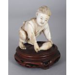 A JAPANESE MEIJI PERIOD IVORY OKIMONO OF A KNEELING BOY, mounted on a fixed wood base, the boy