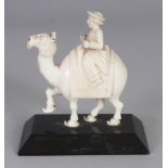 A 19TH CENTURY INDIAN IVORY CARVING OF A CAMEL RIDER, mounted on a polished slate plinth, the plinth