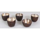 A GROUP OF FIVE 19TH CENTURY CHINESE COCONUT CUPS, with fitted silver liners, the widest 2.5in