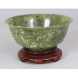 AN EARLY 20TH CENTURY CHINESE MOTTLED GREEN HARDSTONE BOWL, possibly jade, together with a fitted