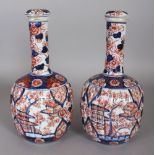 A PAIR OF JAPANESE MEIJI PERIOD IMARI FLUTED PORCELAIN BOTTLE VASES & COVERS, 10.25in high overall.