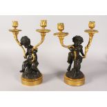 A VERY GOOD PAIR OF REGENCY BRONZE AND ORMOLU TWO-LIGHT CANDLESTICKS, as fauns holding ornate