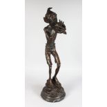AN AMUSING BRONZE OF A PIXIE, standing on a rock, blowing into a shell, on a circular marble base.