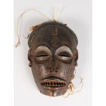 A PAINTED TRIBAL MASK with sharp teeth.