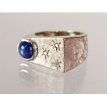AN UNUSUAL 14CT WHITE GOLD DRESS RING set with a cabochon sapphire and diamond.