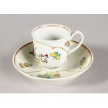 AN 18TH CENTURY WORCESTER COFFEE CUP AND SAUCER painted with flowers in an arabesque panel.