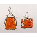 TWO SILVER AND AMBER PENDANTS.