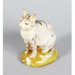 A RARE LOWESTOFT PORCELAIN FIGURE OF A CAT, CIRCA. 1780, on a green base. 2.5ins high. See Godden (