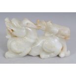 A CHINESE WHITE JADE MODEL OF A DRAGON, with its cub, the stone with ochre inclusions, 3.8in