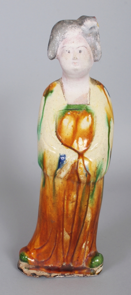 A CHINESE TANG STYLE GLAZED POTTERY FIGURE OF A STANDING FEMALE ATTENDANT, the base unglazed, 11.