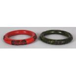 A PAIR OF CHINESE IMITATION HARDSTONE BANGLES, one red, the other green, 3.25in diameter.