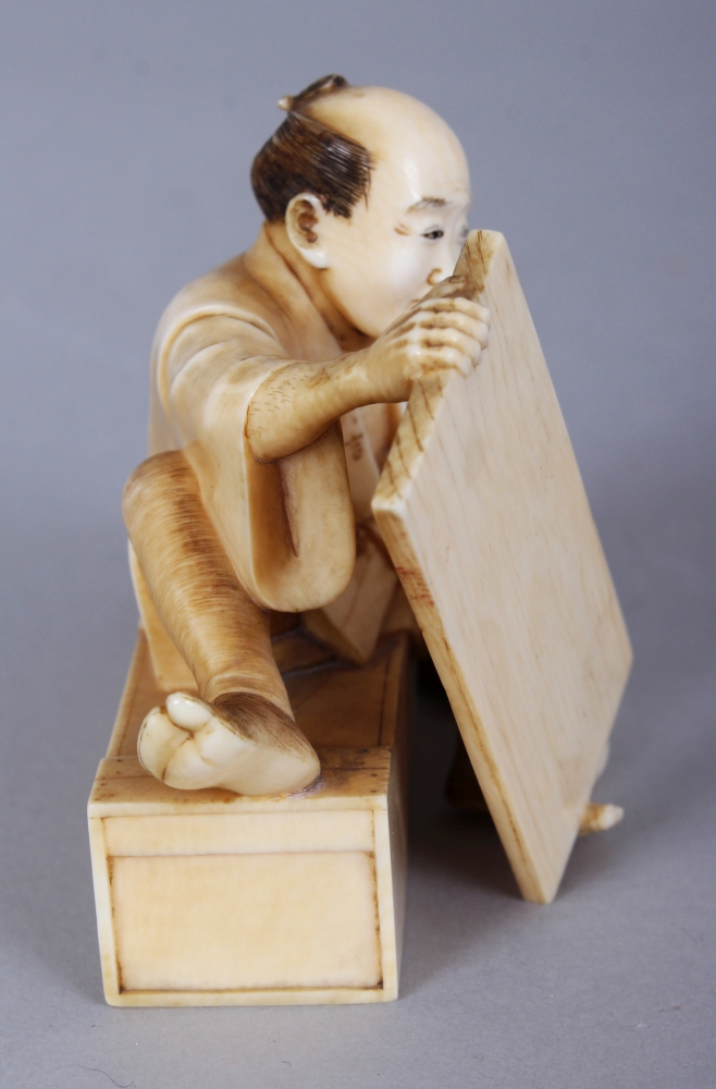 A GOOD QUALITY SIGNED JAPANESE MEIJI PERIOD IVORY OKIMONO OF SEATED CARPENTER, holding between his - Image 2 of 6