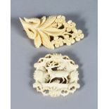 TWO CARVED AND PIERCED IVORY BROOCHES, depicting flowers and a deer.