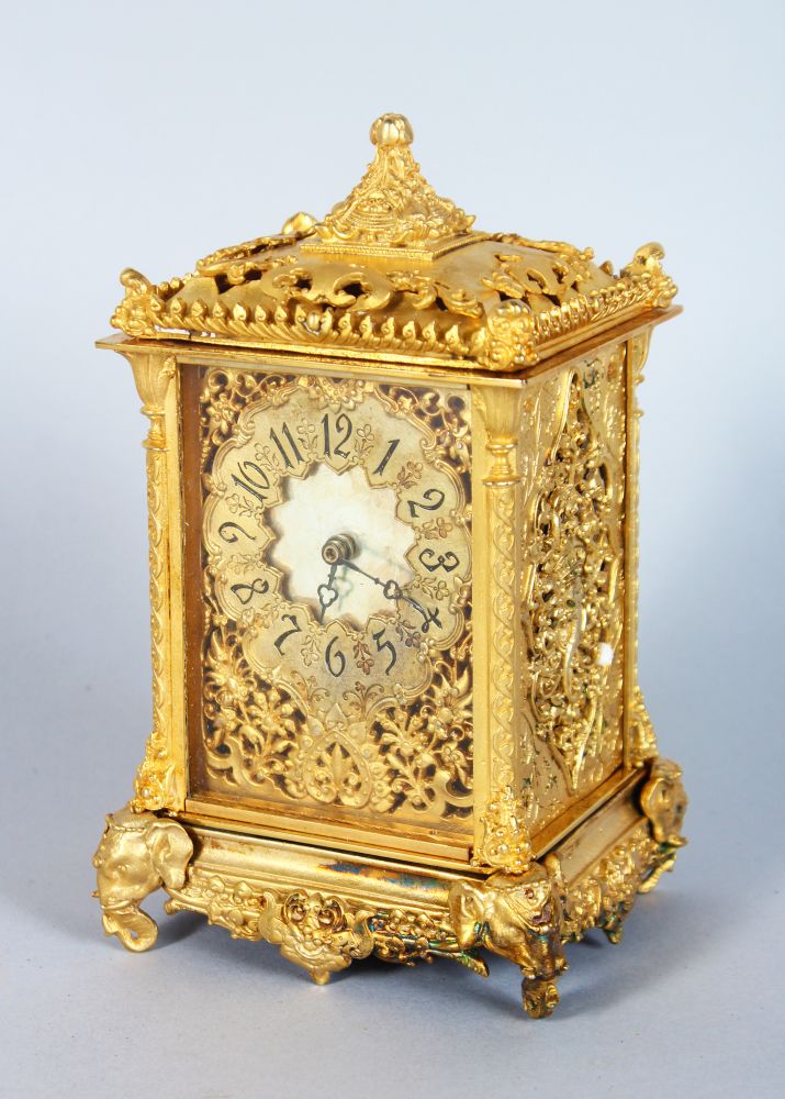 AN ORMOLU CARRIAGE CLOCK, with ornate pierced dial and case, on elephant head feet 7in high