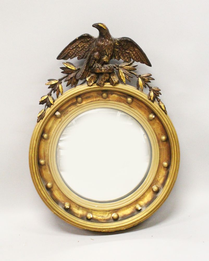 A 19TH CENTURY GILT FRAMED CONVEX MIRROR, with carved eagle cresting, ball finial applied frame. 2ft