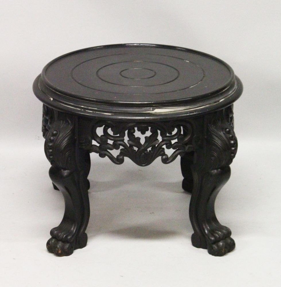 A 20TH CENTURY CHINESE BLACK LACQUER CIRCULAR STAND, with a pierced and carved frieze on four carved