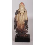 A 20TH CENTURY CHINESE SOAPSTONE FIGURE OF A STANDING IMMORTAL, together with a fixed wood stand,