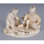 A SIGNED JAPANESE MEIJI PERIOD SECTIONAL IVORY OKIMONO OF A YOUTH & A BOY, collecting clams and