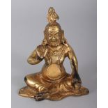 A SMALL TIBETAN GILT BRONZE FIGURE OF KUBERA, seated and holding a mongoose in one hand, the base