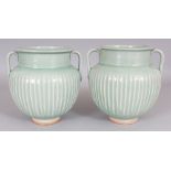 A PAIR OF CHINESE STYLE CELADON FLUTED TWIN-HANDLED PORCELAIN JARS, possibly Islamic, each base with