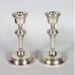 A SMALL PAIR OF SILVER CIRCULAR CANDLESTICKS on loaded bases. 5ins high.