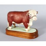 A ROYAL WORCESTER HEREFORD BULL, modelled by DORIS LINDER 1959, on a wooden base. 6ins long.
