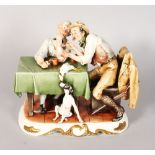 A CAPODIMONTE PORCELAIN GROUP, two men sitting at a table with a dead chicken, a dog under the