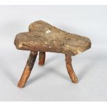 A RUSTIC ROOTWOOD STOOL, with shaped top on three rustic legs. 12ins long x 10ins high.