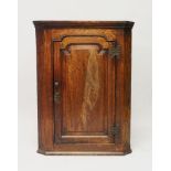 A GEORGE III OAK HANGING CORNER CUPBOARD, with a panelled door enclosing three shelves. 2ft 11ins