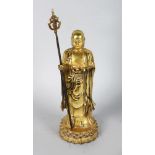 A CHINESE GILT BRONZE STANDING GOD FIGURE holding a staff. 10ins high.