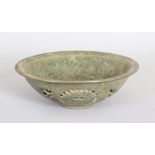 A CHINESE GREEN CELADON POTTERY BOWL, with pierced decoration. 7ins diameter.