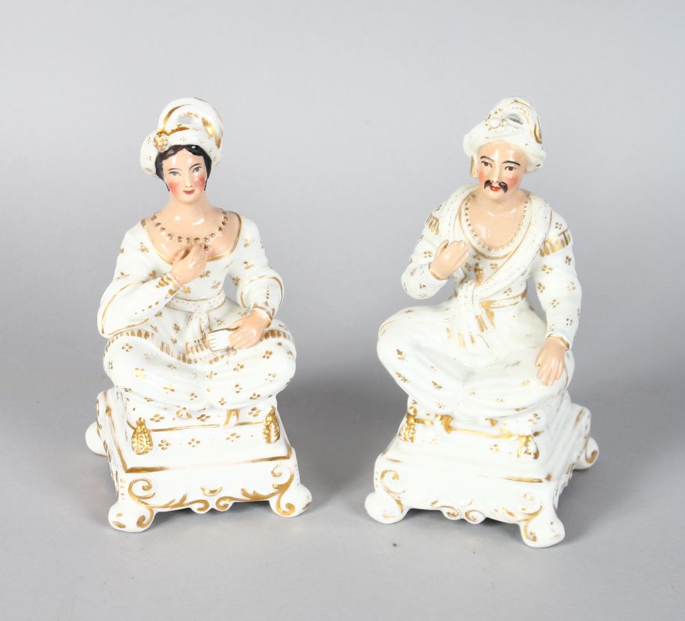A PAIR OF SEATED FIGURES OF A TURKISH MAN AND WOMAN sitting cross legged on stools. 6ins high.