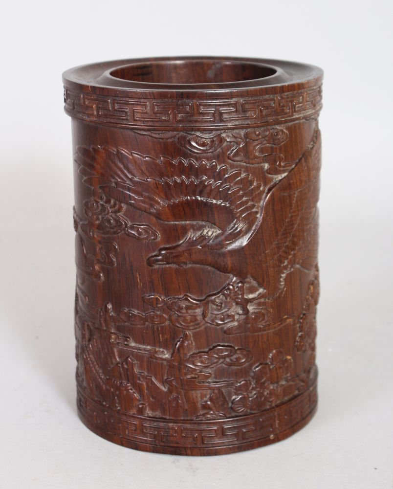 A CHINESE CARVED ROSEWOOD BRUSHPOT, carved with an eagle on a mountainous landscape. 6ins high.