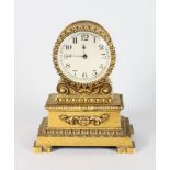 A SMALL EMPIRE GILT METAL CLOCK. 7ins high.