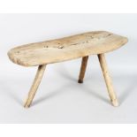 A LONG RUSTIC WOODEN STOOL, with solid top on three rustic legs. 20ins long x 10ins high.