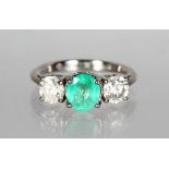AN 18CT WHITE GOLD THREE STONE EMERALD AND DIAMOND RING.