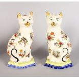 A PAIR OF STAFFORDSHIRE SEATED CATS, painted with flowers. 10.5ins high.