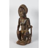 A GOOD CARVED WOOD TRIBAL SEATED MAN holding a knife. 15ins high.