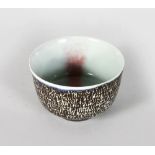 A SMALL CIRCULAR BOWL by RUPERT SPIRA, dark brown matt glaze with blue glazed rim, the body with