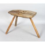 A RUSTIC RECTANGULAR TOP MILKING STOOL, 13ins long, on three rustic legs.