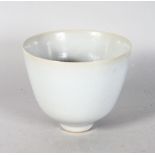A CIRCULAR BOWL OR VASE by RUPERT SPIRA, of tapering form, with a pale grey glaze, on a footed base,