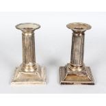 A PAIR OF CANDLESTICKS on square loaded bases. 4.5ins high. London 1909. Makers: W. Hutton & Sons