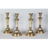 A VERY GOOD SET OF FOUR SILVER GILT CANDLESTICKS on circular bases, with cast acanthus leaves. 12ins
