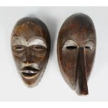 TWO AFRICAN CARVED WOOD MASKS, with pierced eyes, with carved incised patterns, each with a dark