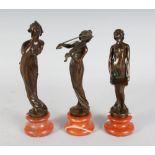 A SET OF THREE ART NOUVEAU STYLE BRONZE FEMALE FIGURES, on circular marble bases. 9ins high.