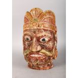 A PAINTED INLAID DEITY WOODEN HEAD. 13ins high.