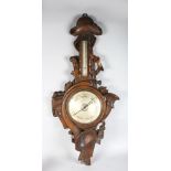 A RARE EARLY 19TH CENTURY BLACK FOREST CARVED WOOD BAROMETER, the case carved with hunting horns,