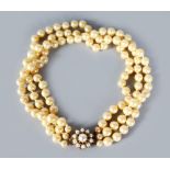 A TRIPLE STRAND PEARL NECKLACE with gold and pearl clasp.